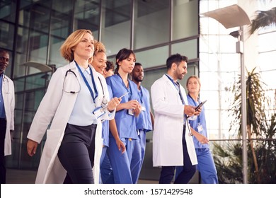 Medical Team Walking Through Lobby Of Modern Hospital Building