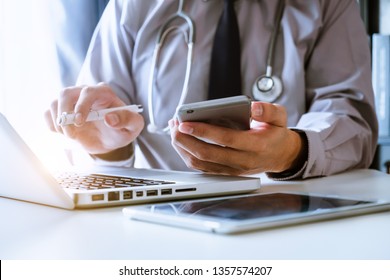 Medical technology concept. Doctor working with mobile phone and stethoscope and digital tablet laptop in modern office at hospital in morning light
