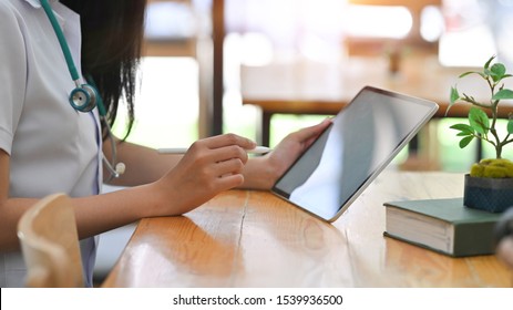 Medical Technology , Cropped Shot Doctor Reading A Report In Tablet Computer On Workplace.