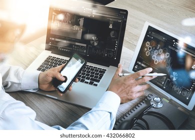 Medical technology network concept. Doctor hand working with smart phone modern digital tablet and laptop computer with chart interface, Sun flare effect photo - Powered by Shutterstock