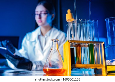 Medical test tubes close-up. Flasks in a medical laboratory. Girl with a tablet in the background. Concept - sale of labware. Micro biology. Reagents on the pharmacologist's desk. Drug making