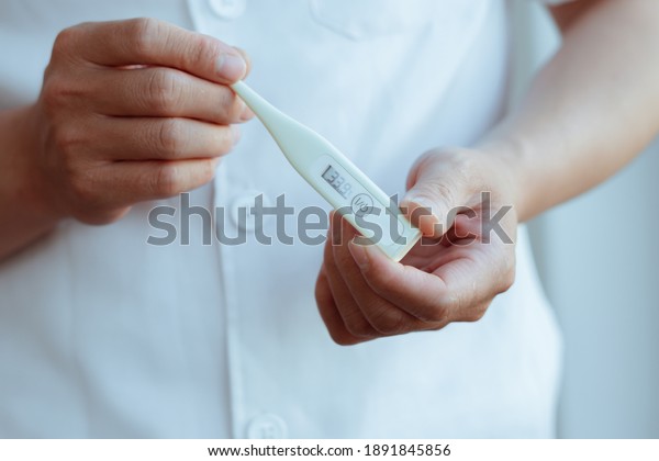 Medical\
thermometer in palm, hand of a doctor or\
nurse.