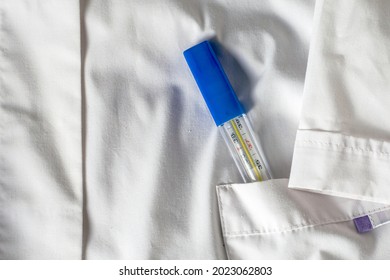 Medical Thermometer In The Side Pocket Of A White Medical Coat. High Quality Photo