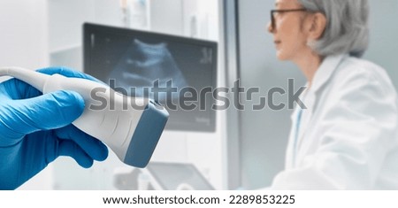 Medical ultrasound probe from ultrasonic machine in doctor's hand on background ultrasound specialist while ultrasound procedure