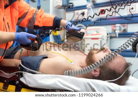 Medical urgency in the ambulance. Emergency doctor using defibrillator