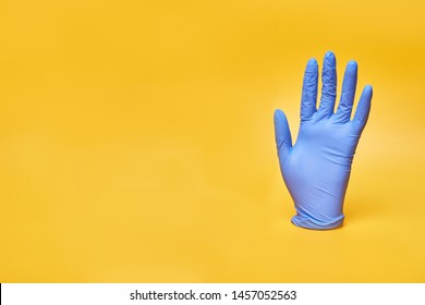 Medical Vinyl, Latex Or Nitrile Glove On Yellow Background.