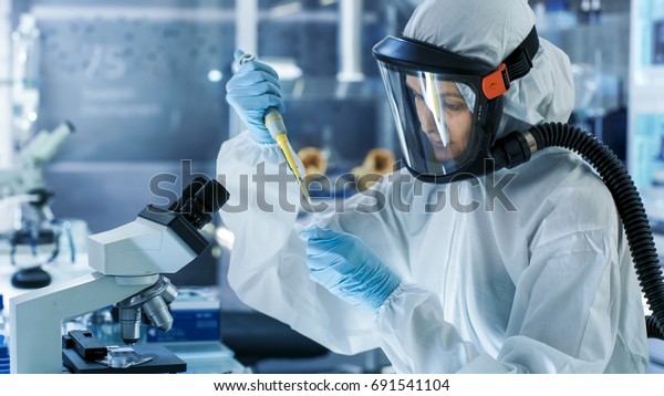 医学ウイルス研究科学者は マスクとハズマットスーツで マイクロピペットを使用しています 彼女は無菌のハイテク研究所 研究施設で働いている の写真素材 今すぐ編集