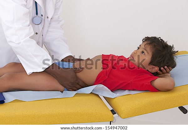 Pediatrician Palpating Stomach Of Little Child Stock Photo 