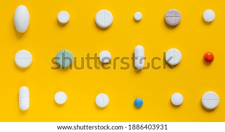 
Medical white pills on a yellow background. Pharmaceutical concept