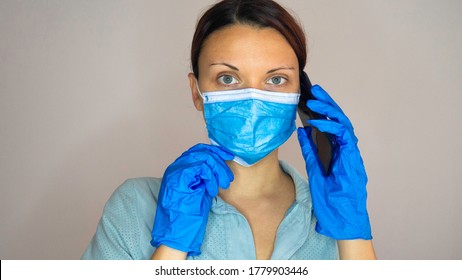 Medical Woman Doctor Or Nurse Wearing Protective Mask And Latex Gloves While Talking On Mobile Phone.