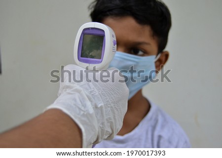 Medical worker checking young man's temperature with infrared thermometer at hospital waiting room. corona virus vaccination, covid 19 immunization concept