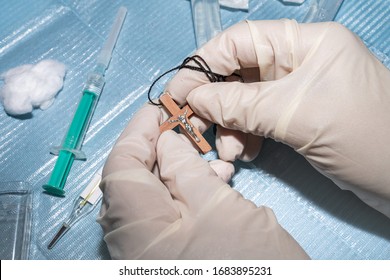 medical worker with gloves holds a wood cross with Jesus and prays for the coronavirus to stop - Shutterstock ID 1683895231