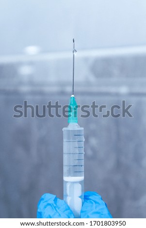 Medical worker holding a syringe with a needle. Nurse with blue latex gloves holding a syringe with a needle.