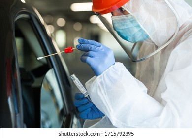Medical worker in personal protective equipment swabbing a person in a car drive through Coronavirus COVID-19 mobile testing center,oral and nasal specimen collection procedure,health and safety  - Shutterstock ID 1715792395
