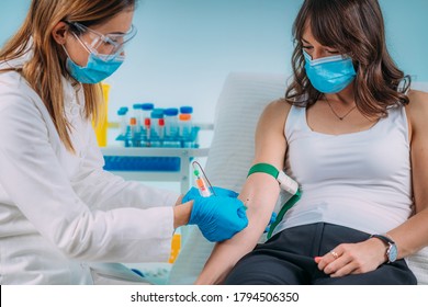 Medical worker with PPE taking blood sample from patient in a hospital 