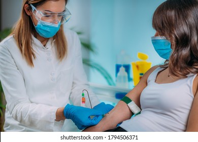 Medical worker with PPE taking blood sample from patient in a hospital 