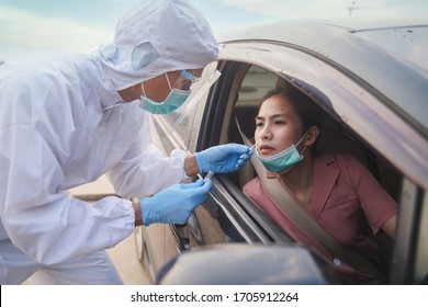 Medical Worker In Protective Suit Screening Woman Driver To Sampling Secretion To Check For Covid-19. Drive Thru Test Coronavirus Fast Track. Concept Prevention Coronavirus Outbreak.