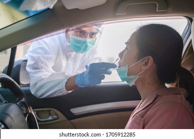 Medical Worker In Protective Suit Screening Woman Driver To Sampling Secretion To Check For Covid-19. Drive Thru Test Coronavirus Fast Track. Concept Prevention Coronavirus Outbreak.