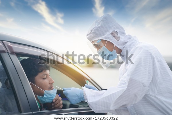 Medical worker in\
protective suit screening driver to sampling secretion to check for\
Covid-19. Drive thru test coronavirus fast track. Concept\
prevention coronavirus\
outbreak.