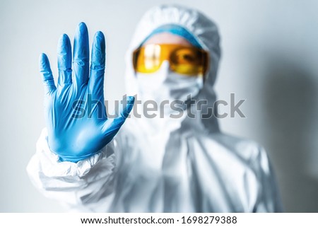 Medical worker in protective suit shows stop sign. Biological hazard. Epidemic of the Chinese coronavirus.