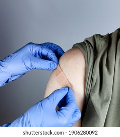 Medical Worker Putting Band Aid On Male Upper Arm After Coronavirus Vaccine Shot 