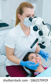 Medical Worker In Rubber Gloves And Medical Mask Using A Microscope While Conducting Root Canal Therapy