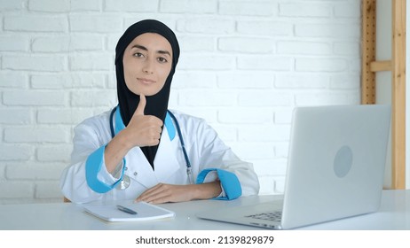 A Medical Worker Shows A Thumbs Up In The Office Where He Receives Patients. A Muslim Woman Works As A Doctor. A Student At A Medical University Is Doing An Internship At A Hospital. Masked Doctor.