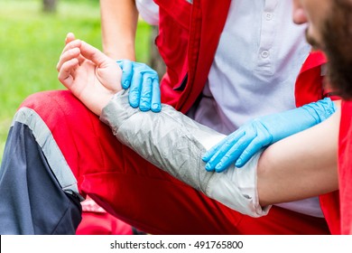 Medical Worker Treating Burns On Male's Hand. First Aid Treatment Outdoors. First Aid Practice