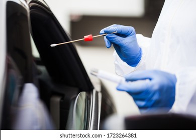 Medical worker wearing personal PPE surgical gloves and protective clothing,holding nasal swab,performing drive-thru COVID-19 testing,point of care on site location for PCR detection of Coronavirus  - Powered by Shutterstock