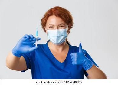 Medical workers, covid-19 pandemic, coronavirus concept. Smiling female doctor, physician in face mask, rubber gloves prepare syringe with vaccine for injection, making flu shot, thumbs-up - Powered by Shutterstock