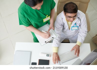 Medical Workers Having Online Meeting With Colleagues And Writing Down Importain Details Of Conversation, View From Above