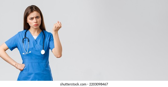 Medical Workers, Healthcare, Covid-19 And Vaccination Concept. Angry And Grumpy Young Female Nurse, Doctor Scolding Young Patient Breaking Quarantine Rules, Shaking Fist In Threat