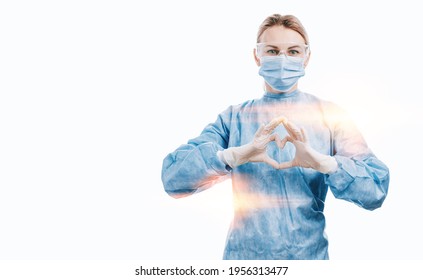 Medical Workers Heroes. A Nurse In A Mask And Uniform Holds Hands In The Shape Of A Heart. Nurses Day Celebration Concept