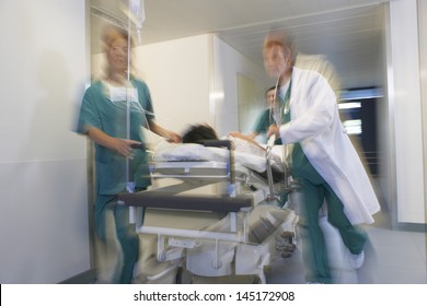 Medical workers moving patient on gurney through hospital corridor - Powered by Shutterstock