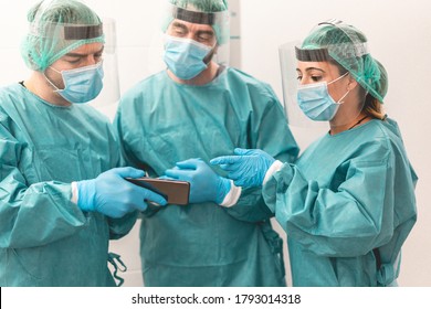 Medical workers using mobile phone inside hospital corridor during coronavirus outbreak - Doctor and nurse at work on Covid-19 crisis period - Health care concept - Main focus on woman hand