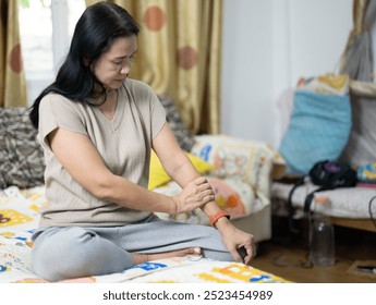 Medical, wrist discomfort, elderly on a sofa with osteoporosis, fibromyalgia, and arthritis. At home, a couch, a woman receiving hand massages for pain, bruising, carpal tunnel syndrome in retirement - Powered by Shutterstock