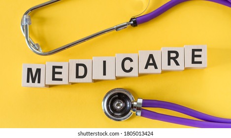 Medicare word written on cube shape wooden blocks on yellow table with stethoscope