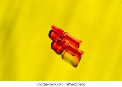 Medication Capsules With Pink Liquid On A Yellow Background. Liquid For Injections Vitamin B. 