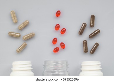 Medicinal capsule spill out of a three plastic bottles on a light surface