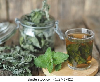 Medicinal herbal tea using dried Melissa. Dried leaves of Melissa or mint with a fresh twig and decoction in a glass on an ancient wooden table. - Shutterstock ID 1727467822