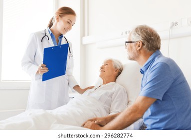 Medicine, Age, Health Care And People Concept - Senior Woman, Man And Doctor With Clipboard At Hospital Ward