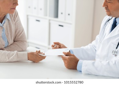 Medicine, Age, Healthcare And People Concept - Close Up Of Senior Woman And Doctor With Prescription Or Referral At Hospital