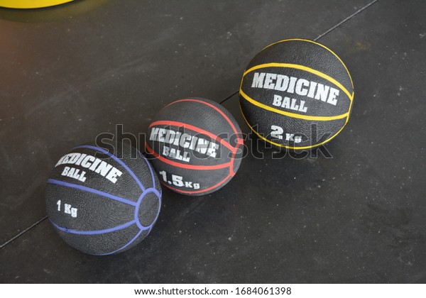 Medicine balls in blue red and yellow on black\
concrete floor in gym sport\
school