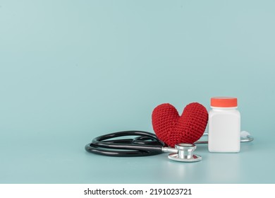 Medicine Bottle And Pill With Stethoscope And Red Heart Shape Concept Of Health Care And Medical. Aspirin Bottle And Stethoscope And Yarn Heart On Light Blue Background.