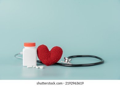 Medicine Bottle And Pill With Stethoscope And Red Heart Shape Concept Of Health Care And Medical. Aspirin Bottle And Stethoscope And Yarn Heart On Light Blue Background.