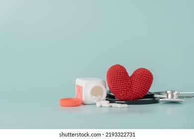 Medicine Bottle And Pill With Stethoscope And Red Heart Shape Concept Of Health Care And Medical. Aspirin Bottle And Stethoscope And Yarn Heart On Light Blue Background.