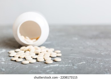 Medicine Bottle And White Pills Spilled On A Light Background. Medicines And Prescription Pills Flat Lay Background. White Medical Pills And Tablets Spilling Out Of A Drug Bottle.