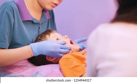 Medicine Clinic. A Baby With Cerebral Palsy Disease Receiving A Muscle Face Massage With A Special Instrument. Speech Therapy Massage