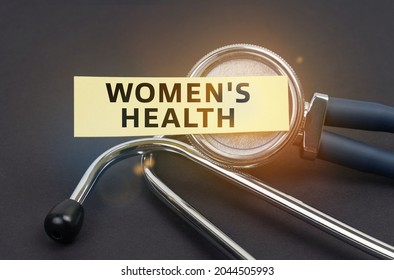 Medicine concept. On a black background, a stethoscope, on which a sticker with the inscription - WOMEN S HEALTH