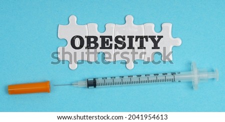 Medicine concept. On a blue background, a syringe and puzzles with the inscription - OBESITY